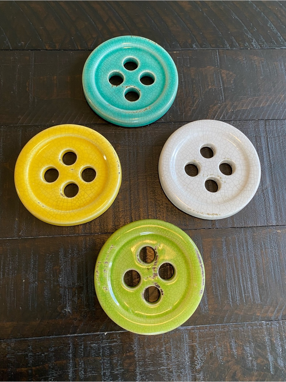 This is a set of four multicolored ceramic button-shaped coasters.